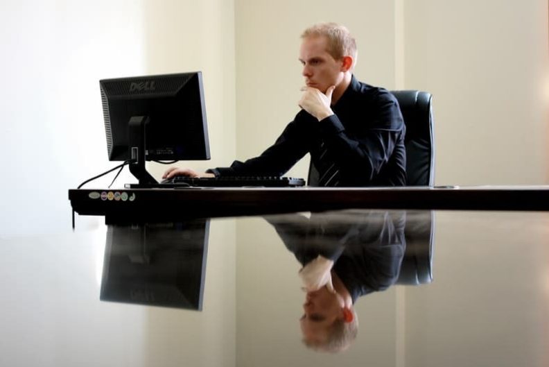 businessman sitter ved en pc og vurderer om han skal ha ny nettside